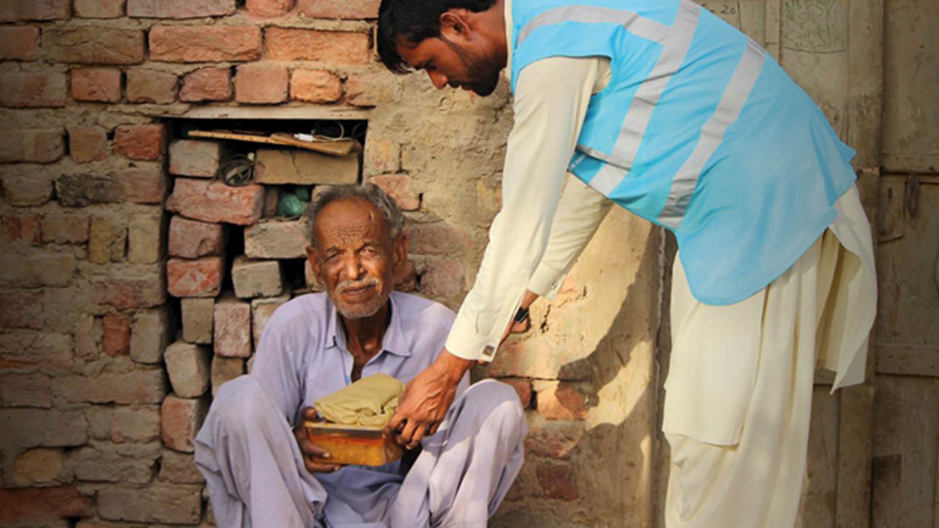  A Muslim man is giving sedekah charity to an elderly man.